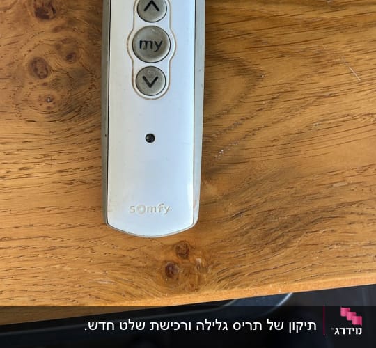 שלט רחוק לשליטה בתריסים על שולחן עץ